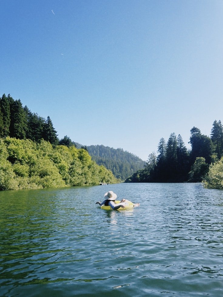 Person relaxing on a float in a calm forest lake