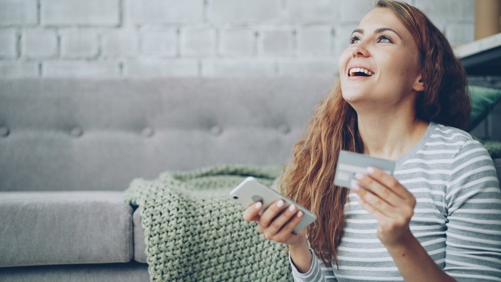 Customer holding a card while reviewing a payment on a phone
